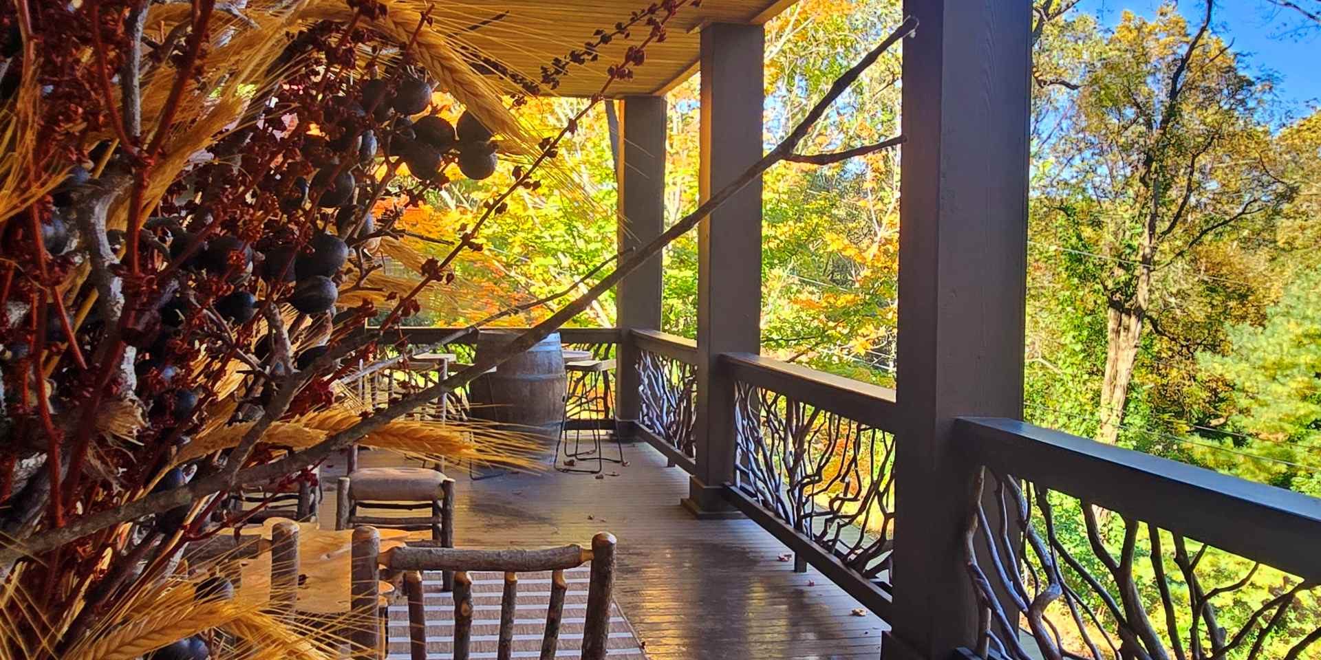 North Georgia fall getaway - Wooden porch with a trough of orange pumpkins and dried grasses, set against autumn foliage and a blue sky.