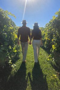 Couple walking hand in hand through a sunny vineyard between grapevines
