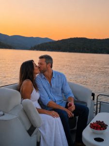 Couple kissing on a boat at sunset, with a lake and forested hills in the background.